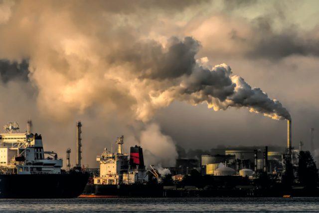 Das Bild zeigt einen Industriehafen mit rauchenden Schloten im Hintergrund.