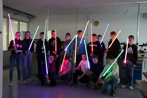 Das Foto zeigt eine Gruppe von 15 Jugendlichen mit ihren bunt leuchtenden Lichtschwertern.