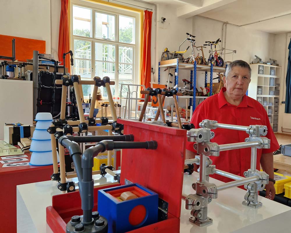 Das Foto zeigt Karin Ressel in einem der Räume des Technikzentrums. Vor ihr stehen verschiedene Gerüstteile, im Hintergrund sieht man ein Regal voller Laufräder.
