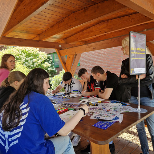Das Foto zeigt eine Schüler:innen-Gruppe, die sich mit Textil-Upcycling beschäftigt.