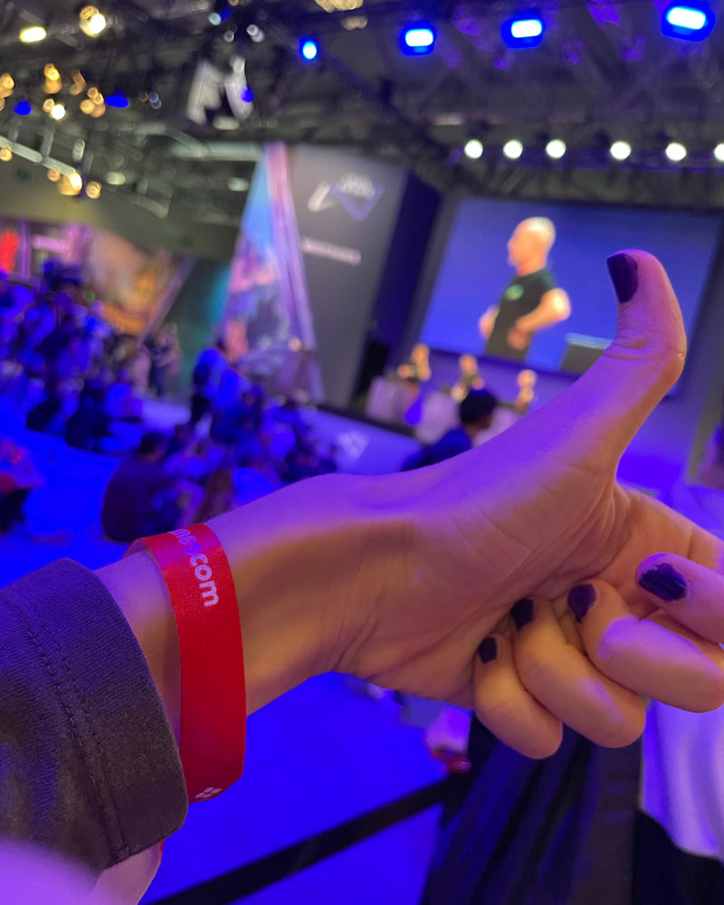 Das Foto zeigt eine Hand, die einen Daumen hoch zeigt, mit einem roten Gamescom-Armband am Handgelenk.