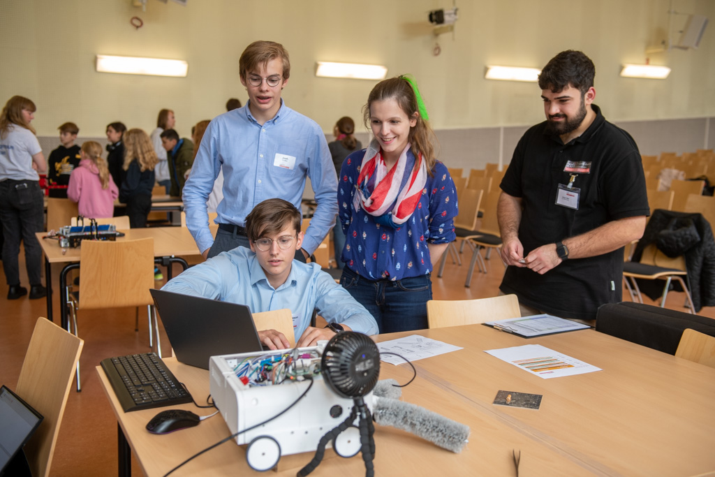 Eine Gruppe von Teilnehmern des zdi-Roboterwettbewerbs steht mit einem Laptop um einen Tisch.
