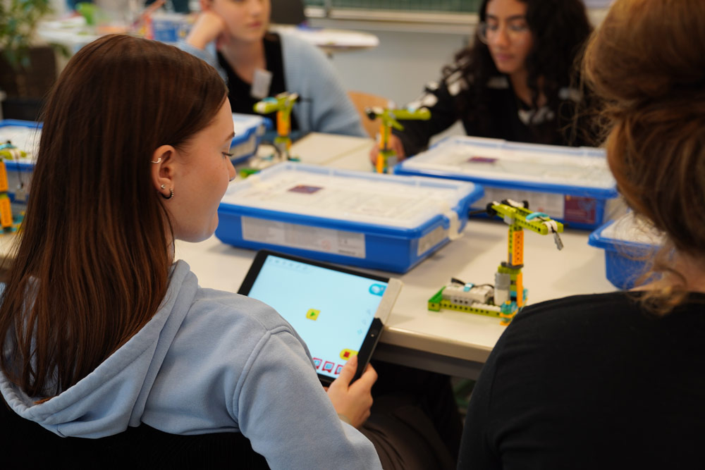 Eine Gruppe Mädchen sitzt beim zdi-Mädchen-Camp mit einem Tablet an einem Tisch.