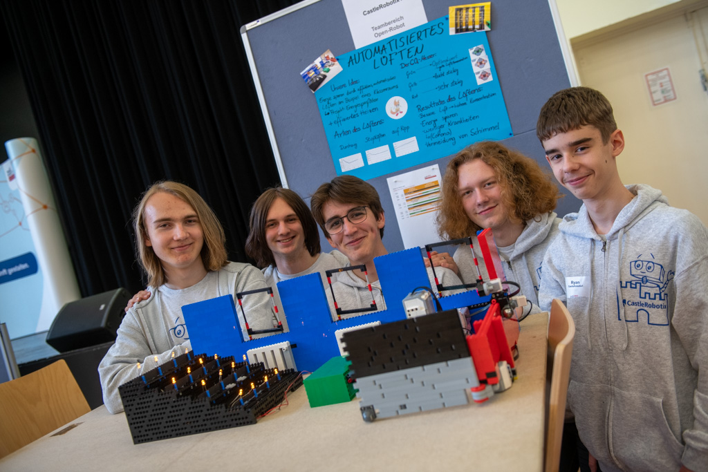 Eine Gruppe junger Menschen posiert beim zdi-Roboterwettbewerb mit ihren Robotern.