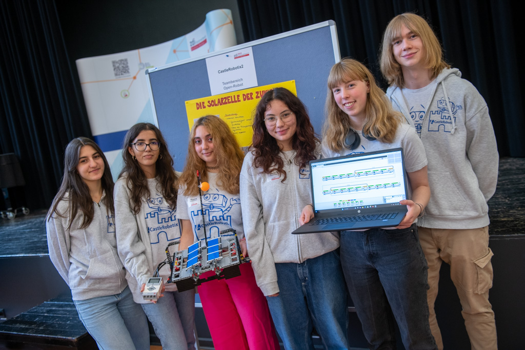 Eine Gruppe junger Menschen, die am zdi-Roboterwettbewerb teilnehmen, posiert mit ihren Laptops.