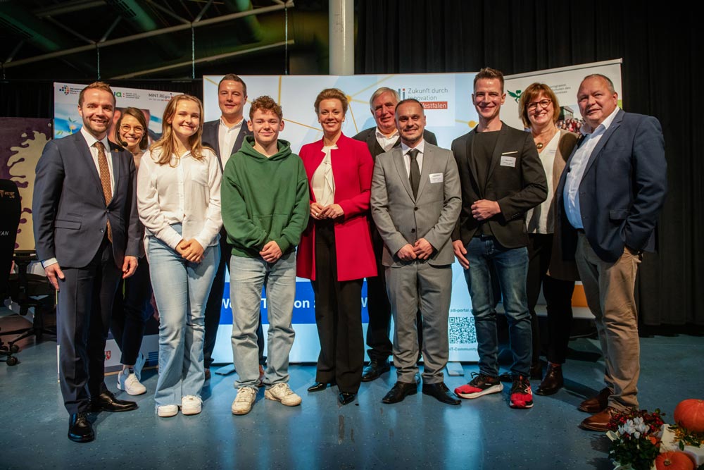 Die Besucher:innen und Teilnehmenden der Gesprächsrunde bei der Eröffnungsveranstaltung des zdi-Technikzentrums Waltrop stehen vor einem zdi-Banner und lächeln in die Kamera.
