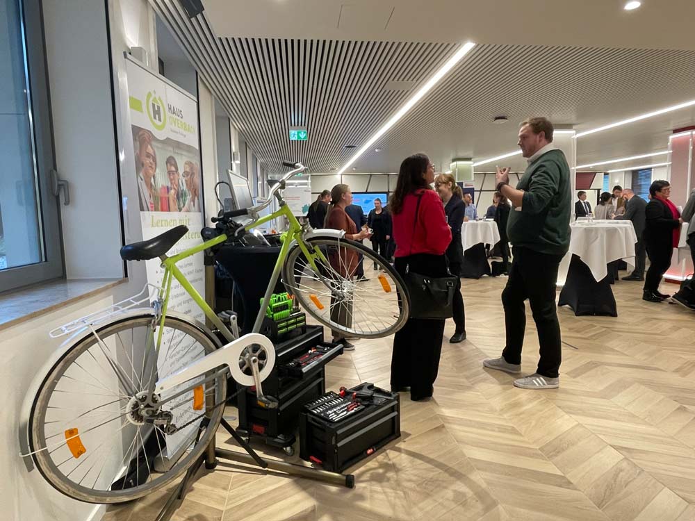 Eine Gruppe von Menschen betrachtet ein ausgestelltes Fahrrad. Das zdi-Netzwerk ANTalive präsentiert hier seine Fahrradwerkstatt zur MINT-Förderung.