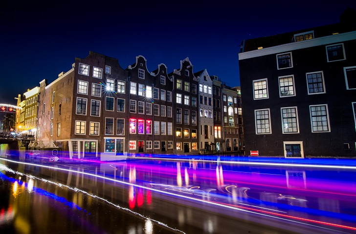 Amsterdam bei Nacht; Lichtreflexe, die durch fahrende Autos entstehen, durchstreifen das Bild. Es wirkt wie eine Datenautobahn.