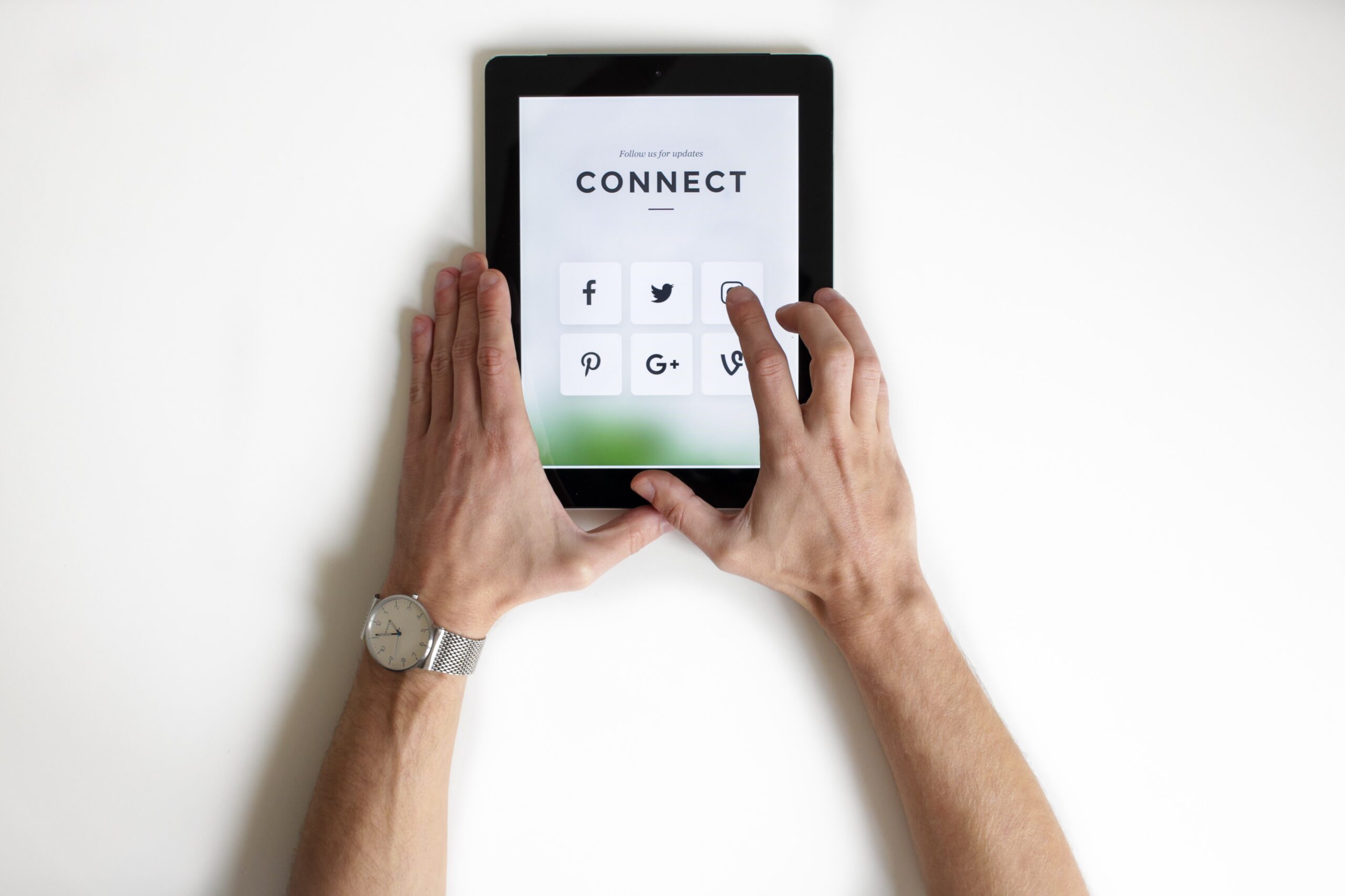 Menschliche Hände berühren ein Tablet auf dem das Wort Connect zu sehen ist.
