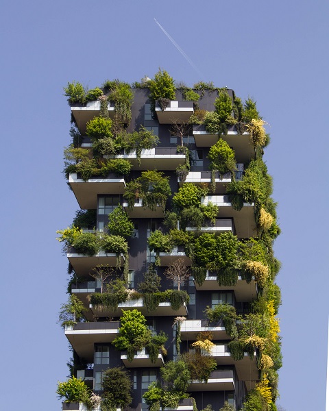 Ein modernes Hochhaus. Die Balkone sind üppig grün bepflanzt, so dass das Haus fast wie ein grüner Quader, der in den Himmel reicht, ausssieht. Das Bild steht symbolisch für das Jahresthema „Lebensräume der Zukunft”.