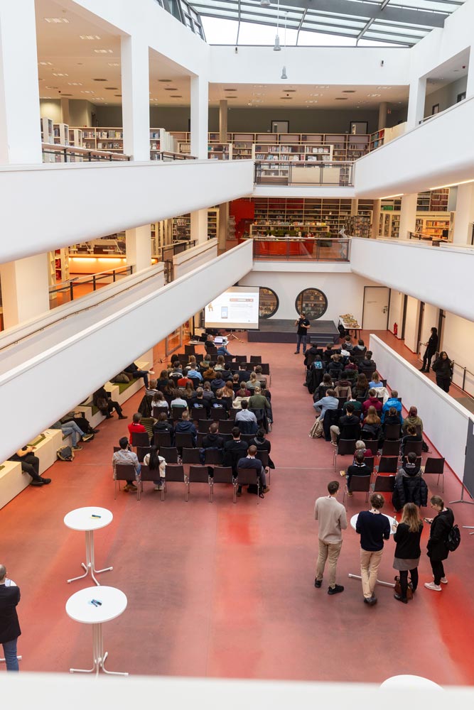 Eine Gruppe von Menschen sitzt in einer großen Bibliothek.