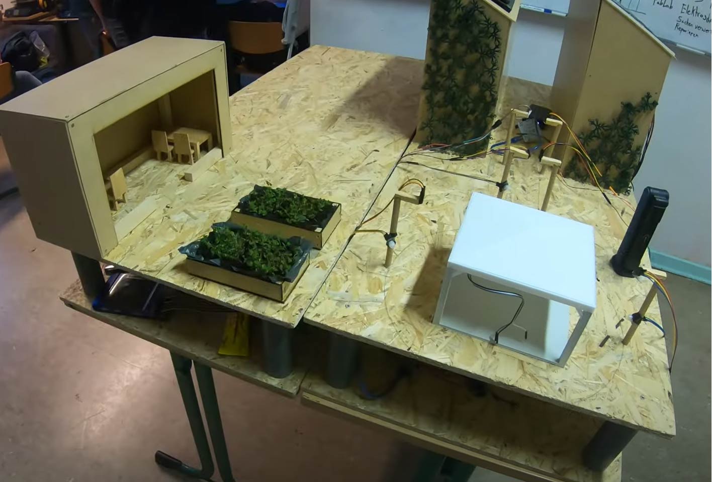 Aufbau eines Science-League-Projekts auf einem Tisch mit elektronischen Bauteilen und Modellvegetation.