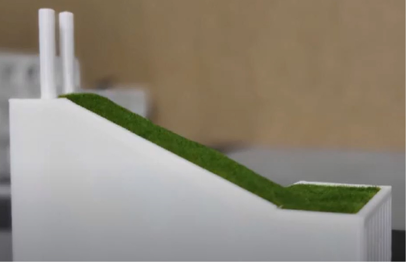 Eine Nahaufnahme eines weißen Objekts mit einer geneigten grünen Oberfläche, das an ein minimalistisches Designmodell erinnert.