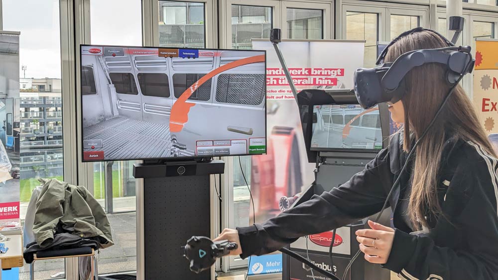 Auf der öffentlichen Ausstellung „Zukunftstag 2024“ setzt eine Frau ein VR-Headset auf. Sie interagiert mit einer Virtual-Reality-Simulation, die das Innere eines Zuges nachbildet.