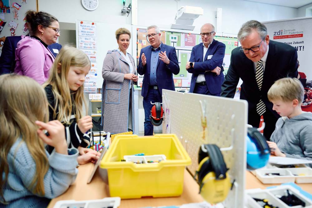 Eine Gruppe Erwachsener beobachtet Kinder, die in einem Klassenzimmer Werkzeuge für Projekte verwenden.