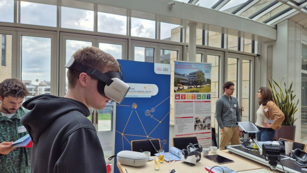 Person mit VR-Brille auf einer Wissenschaftsmesse in einem hellen Glasgebäude