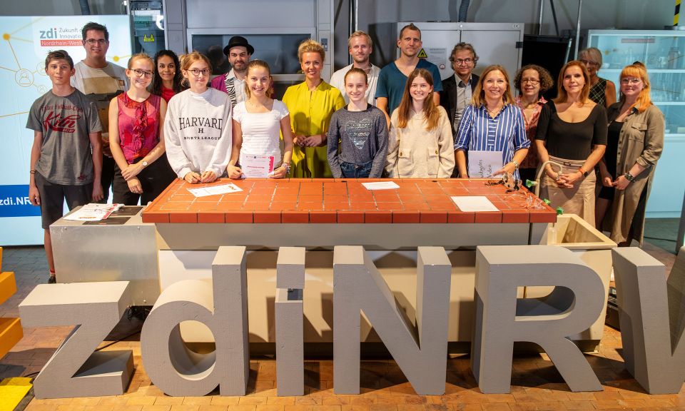 Das Bild zeigt alle Teilnehmenden des Science Video Award 2022. In der Mitte steht Ministerin Ina Brandes.