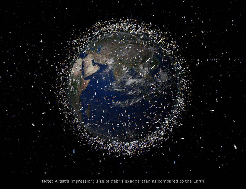 Die Abbildung zeigt die Erde, die von zahlreichen Weltraumtrümmern umgeben ist, wobei die Größe der Trümmer zur Verdeutlichung übertrieben dargestellt ist.