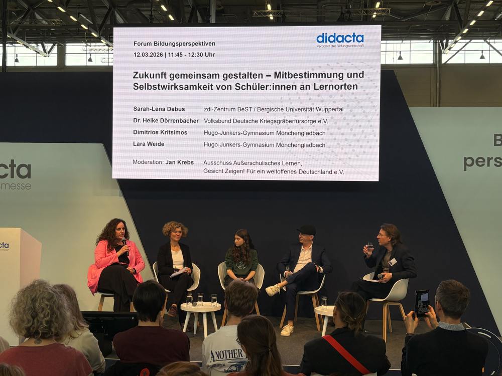 Fünf Podiumsteilnehmer sitzen auf der Bühne der Bildungsmesse Didacta. Eine große Leinwand hinter ihnen zeigt ihre Namen und das Diskussionsthema.
