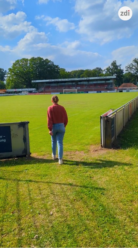 Person geht auf einem Fußballplatz auf das Spielfeld zu