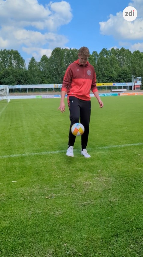 Ein Fußballer im roten Trikot mit Ball.