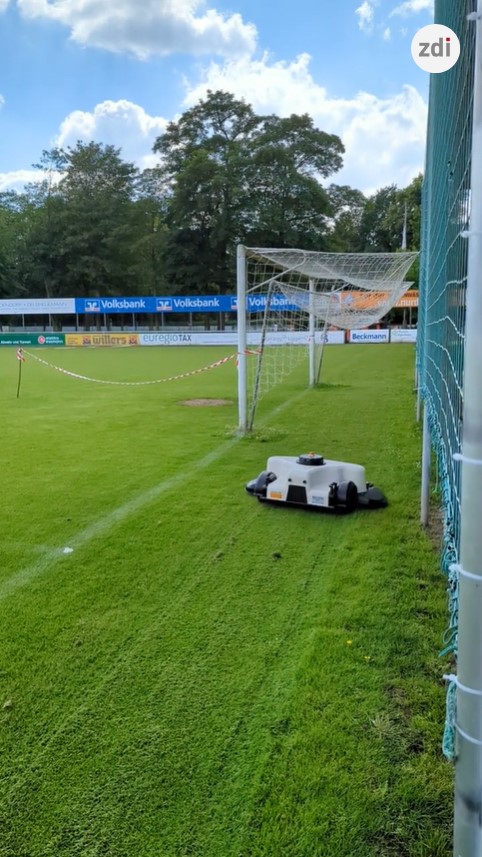 Ein Mähroboter auf dem Fußballplatz.