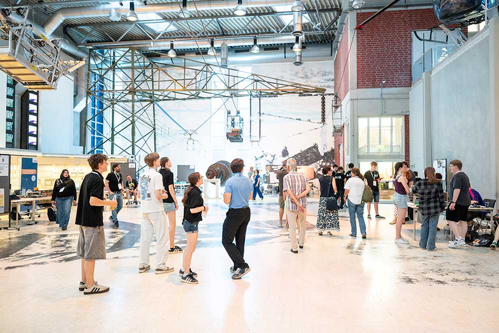 Besuchergruppe in einer großen Ausstellungshalle mit technischen Installationen und Exponaten